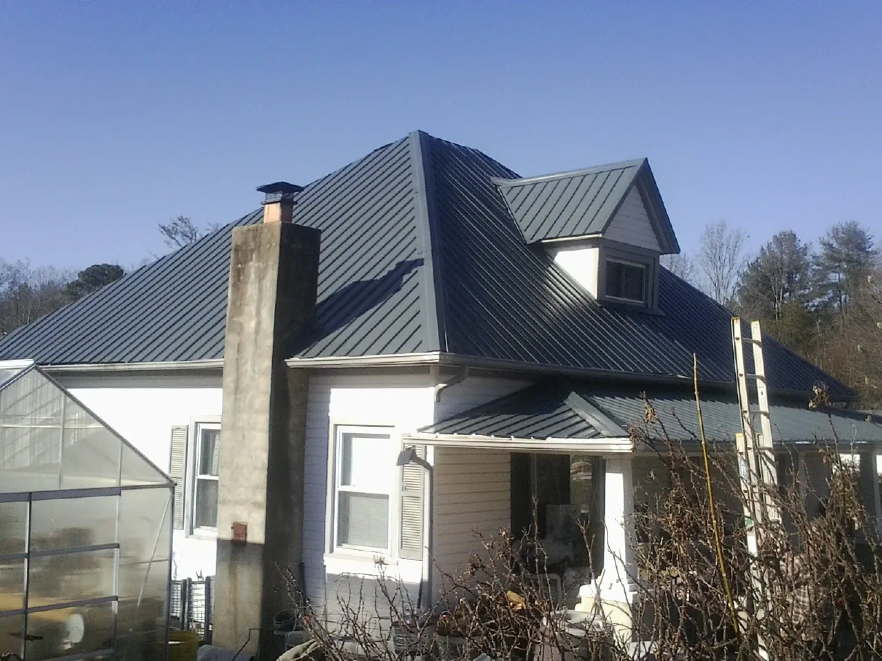Dark blue standing seam metal roof on a white farmhouse with dormer — Slate & Tile Roof Repair by Roofing Brothers in Wauconda