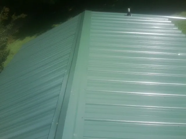 New green metal panels meeting at the ridge of a roof — Flat Roof Repair work by our crew in Wauconda