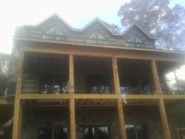 Dormers and porch framing on a large log home under construction — Roof Coating work by our crew in Wauconda
