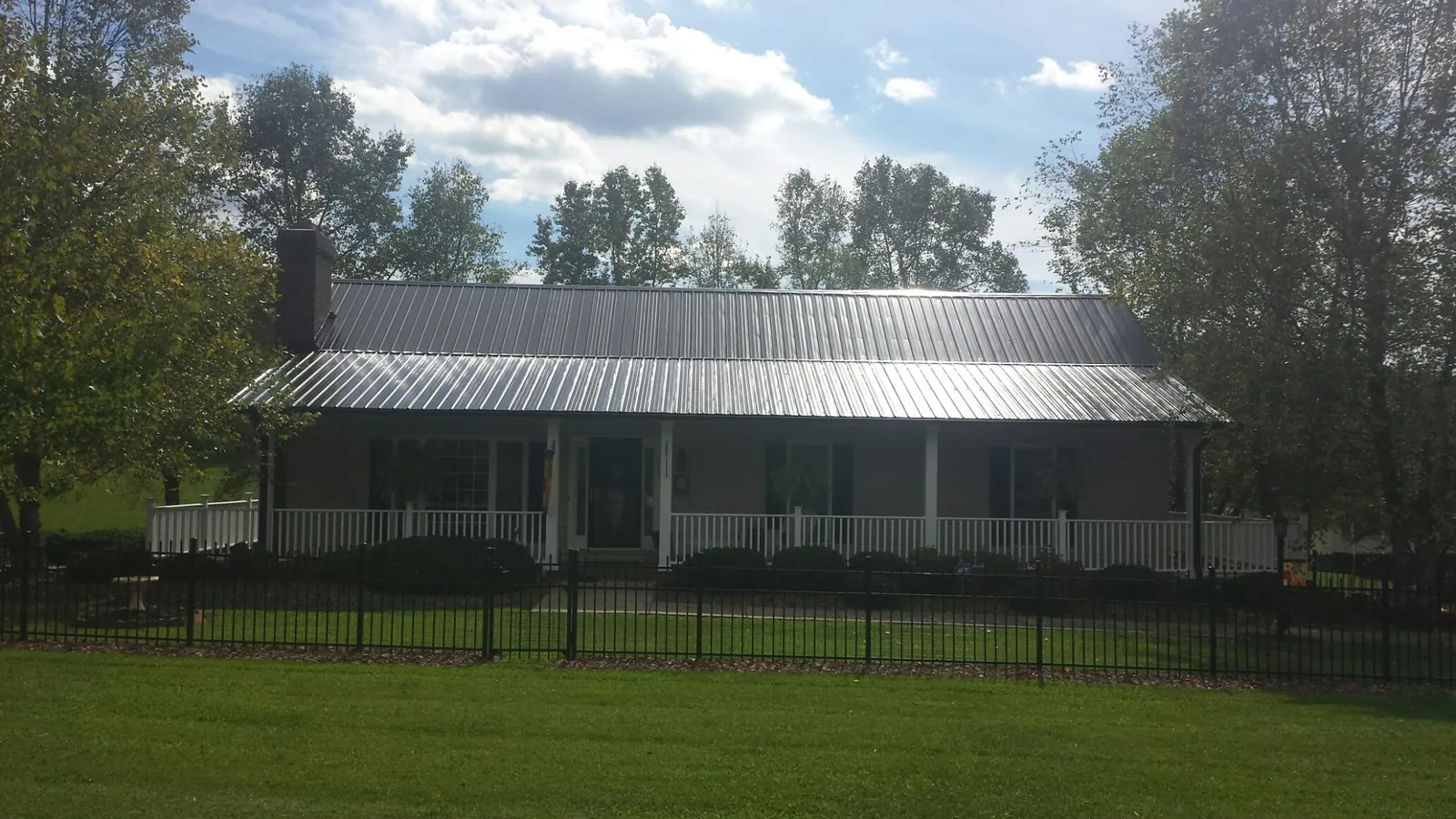 Gray metal roof on a brick ranch with a full width front porch — Gutter Guard Installation work by our crew in Wauconda