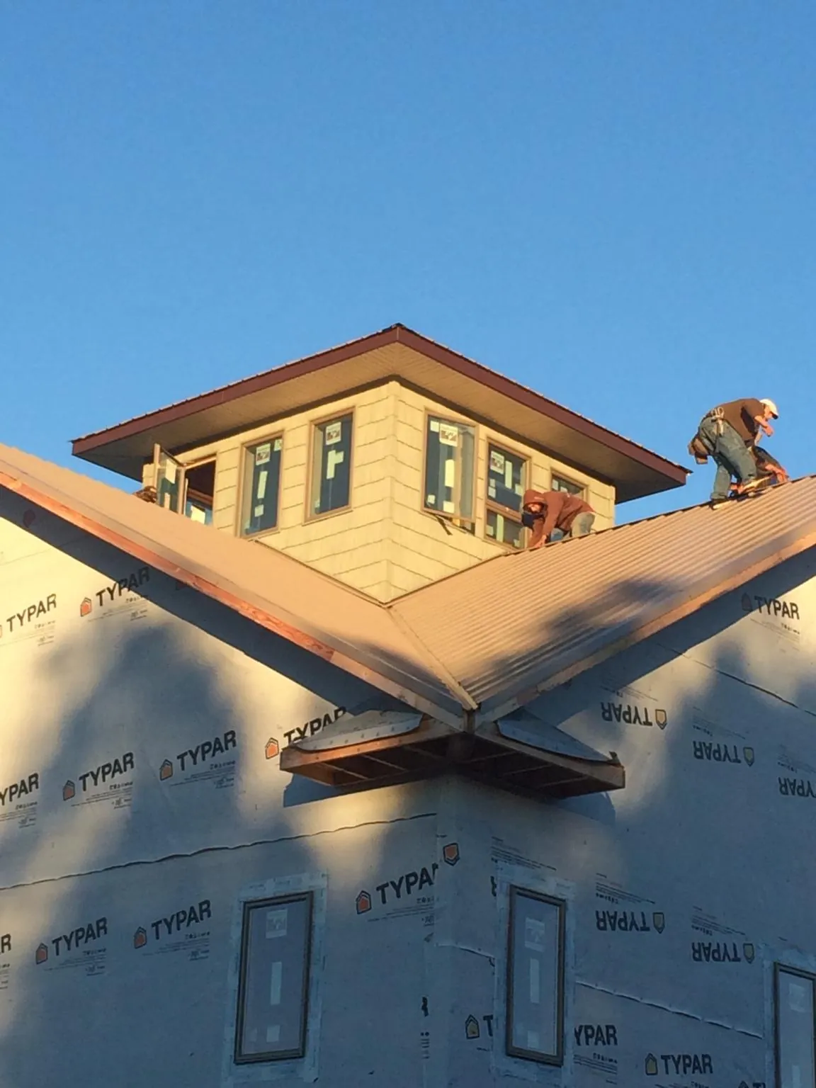 Roofers working around a rooftop cupola on a new metal roof at sunset — Roof Waterproofing in Wauconda by Roofing Brothers